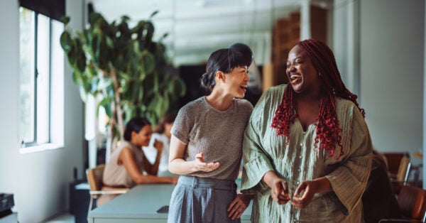 Two coworkers sharing a joyful moment and laughing together during a break in a modern office environment.