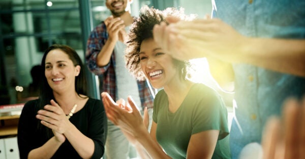 A group of colleagues celebrating their team in a boardroom.