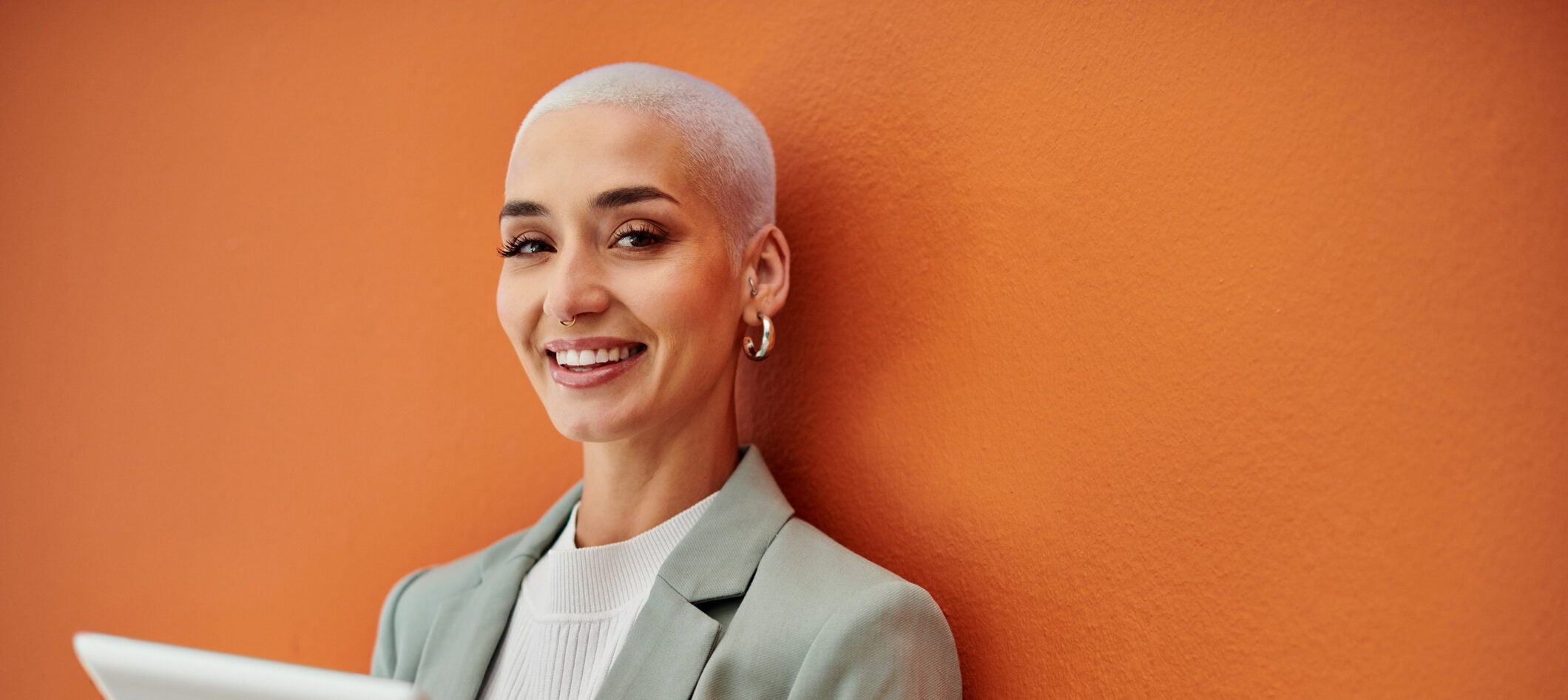 Portrait of a young businesswoman using a digital against an orange background